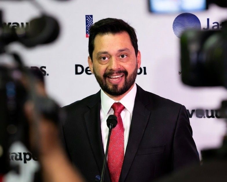 politician standing in front of a branded step and repeat banner during a press conference